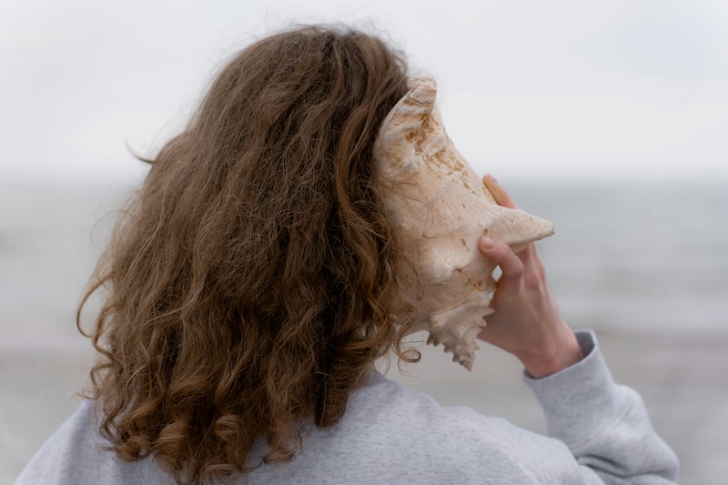 Girl listening to seashell at beach